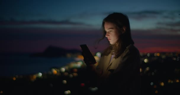 Jonge vrouw kijken naar telefoon in zonsondergang licht — Stockvideo