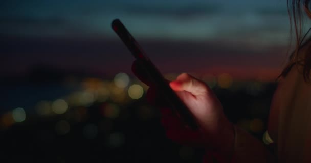 Młoda kobieta patrzy na telefon w świetle zachodu słońca — Wideo stockowe