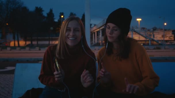 Zwei Freunde hören Musik im Abendlicht — Stockvideo