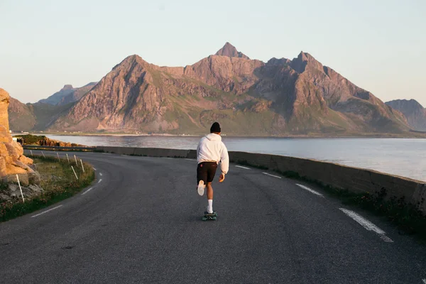 Millennial hipster man ride longboard on epic road — Stock Photo, Image