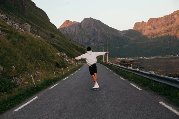 Millennial hipster man ride longboard on epic road Stock Photo
