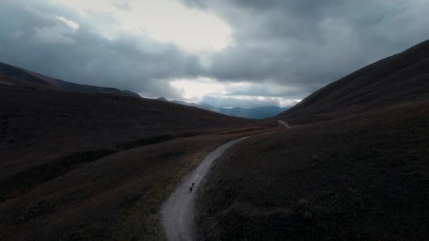 Scenic aerial drone shot of two cyclists traveling — стоковое видео