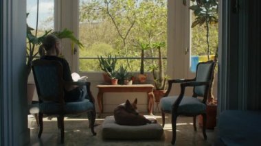Young woman reading at home with adorable view