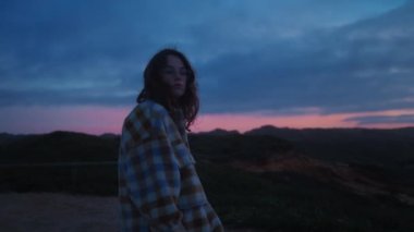 Yakın plan sinematik yumuşak portre esmer, kıvırcık saçlı, rahat, ekose gömlekli, şık gözlüklü güzel bir genç kadın portresi. Romantik kız rüya görüyor, düşünüyor, renkli gün batımını izliyor..