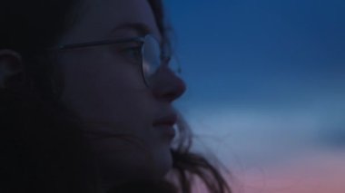 Kapalı sinemada genç bir kadının ya da siyah kıvırcık saçlı bir kızın güneş gözlüğü takan, hayal kuran, düşünen, gün batımında dışarıda dinlenen, gezen ve Porto 'ya seyahat eden bir genç portresi.