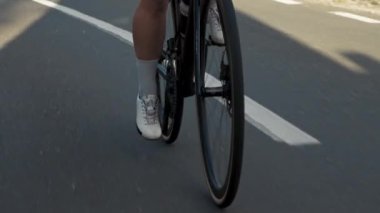 Profesyonel yol bisikletçisi bacaklarına yakın mesafede, genç ve enerjik bir kadın yüksek dağ yolunda bisiklete biniyor günlük aktivitelerde zorlu spor yoğun antrenmanlarında. Sporcular için sağlıklı bir açık hava yaşam tarzı.