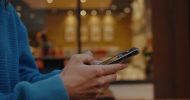 Profil yan görüntüsünü kapatın, genç eller cep telefonu tutuyor, akıllı telefon kullanıyor, mesaj yazıyor, sosyal medyada arkadaşlarla sohbet ediyor, hafta sonları şehir kafesinde dışarıda oturuyor, izinli.