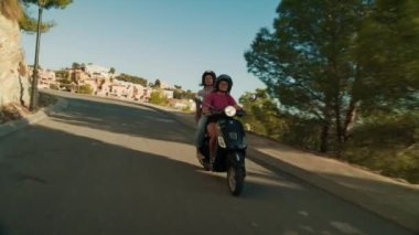 İki genç kadın İtalyan Piaggio 'sunda, Vespa ise İspanya kırsalında dağ yolunda motosiklet sürüyor. Avrupa tatili ve tatil beldesi. ALTEA, İSPAN - MAYIS 2021