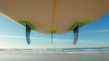 POV shot of surfer carry surfboard towards ocean. Surfing lifestyle in Portugal. Surfboard with fins on warm summer day near sea