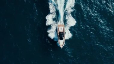 Luxurious yacht breaks waves of pristine dark navy blue ocean waters. Idyllic symmetric background shot of summertime holiday or vacation in mediterranean. Below deck lifestyle of rich and famous