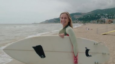 Mutlu gülümseyen otantik sörf tahtası olan genç kadın kameraya bak, kendinden emin gülümse ve kıkırda. Yaz macerası, tatil beldesi California 'da sörf yaşam tarzı