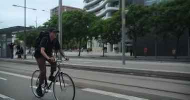 Young handsome man commute to work or school on minimalistic city bike. Student or office worker on way to university or office ride bike on bikelane