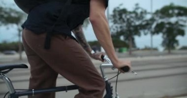 Closeup soft focus shot of young millennial man ride standing up out of saddle on commuter bike on way to work. Cycling in the city on bike lane. Urban mobility and modern city infrastructure