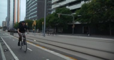 Young millennial man ride his city bicycle on bike lane. Commuting in green way, cycling to work or school. Urban city infrastructure for cyclists and cars. Transportation safety