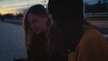 En iyi iki bayan arkadaş gün batımında parkta takılır, müzik dinler ve ritimle dans ederler. Müzik yayın platformu ya da uygulama, iki kadın kulaklıkları paylaşıyor ve eğleniyor, gülümsüyor ve gülüyor. 