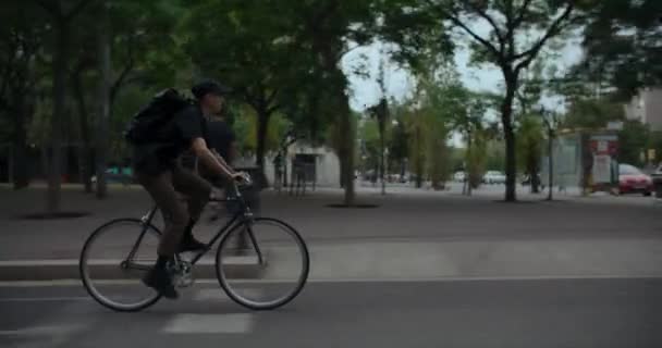 现代城市自行车手在上班路上的侧向跟踪镜头 时尚时髦的男子骑着他的通勤自行车在市区的自行车道上 夏天繁忙的城市生活方式 — 图库视频影像