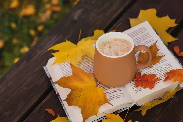 A cup of coffee on a book with yellow leaves