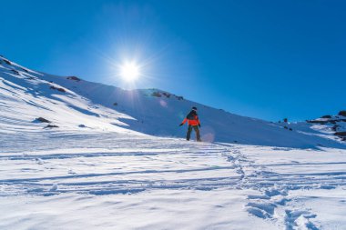 Güneşli bir günde kar kayağı yapan kayakçı açık mavi gökyüzüyle