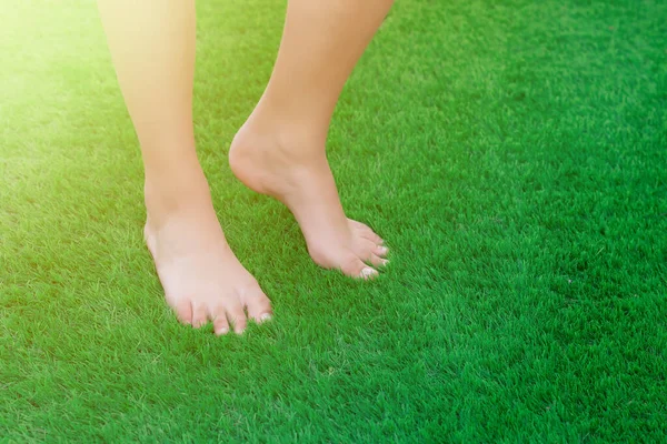 Close-up of bare feet on green artificial turf. Soft, clean and antibacterial artificial grass surface