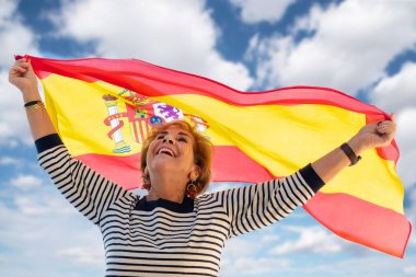 Yaşlı bayan İspanyol olmaktan gurur duyuyor, gülümsüyor ve İspanyol bayrağı sallıyor. Columbus Günü.