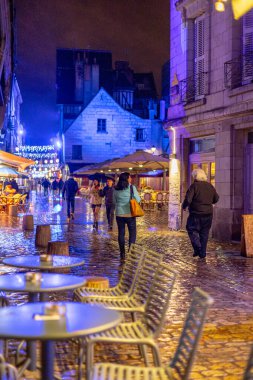 Tur sakinleri, yağmurda yılbaşı aydınlatmalarıyla dekore edilmiş yarı ahşap evlerden inşa edilmiş ortaçağ mimarisi meydanı Place Plumereau 'daki barlarda dinleniyor. Tur, Fransa. 27 Kasım 2021