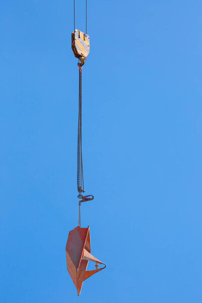Lifting of metal pallet for dry bulk building materials on hoisting block with hook on steel chain on steel rope. Loading\unloading of building materials on construction building site. Development.