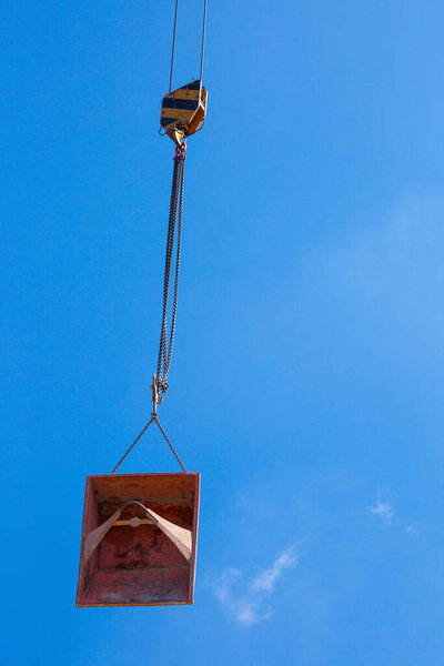 Lifting of metal pallet for dry bulk building materials on hoisting block with hook on steel chain on steel rope. Loading\unloading of building materials on construction building site. Development.