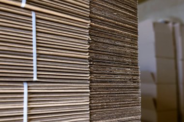 Karton kutuları katlıyorum. Yırtılmış karton çarşaflar paletlerin üzerine istiflenmiş. Endüstriyel üretimde bitmiş ürünlerin ambalajı.