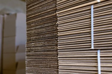 Karton kutuları katlıyorum. Yırtılmış karton çarşaflar paletlerin üzerine istiflenmiş. Endüstriyel üretimde bitmiş ürünlerin ambalajı.