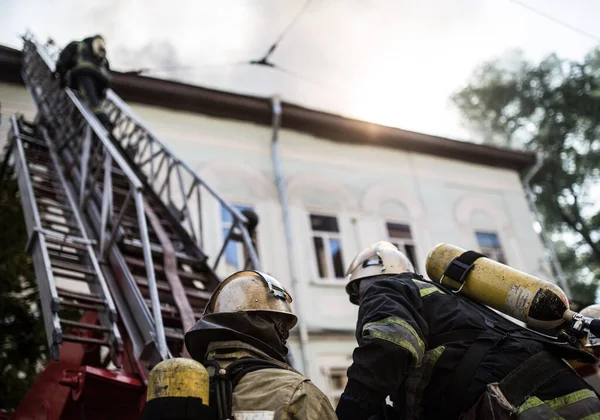 Brandweerlieden Ladders Met Zuurstofmaskers Blussen Het Vuur Een Oud Huis — Stockfoto