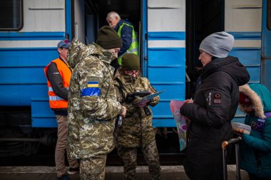 LVIV, UKRAINE - 12 Mart 2022 Ukrayna 'daki savaş sırasında insani yardım felaketi. Sınır muhafızları, küçük çocuklu mültecilerin belgelerini kontrol ediyor. Lviv Tren İstasyonu 'ndaki Avrupa' ya kaçıyorlar..