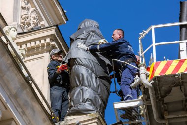 LVIV, UKRAINE - 21 Mart 2022: Lviv Ulusal Operası 'nın ön cephesindeki heykelleri olası bombalamalardan korumak için SES kurtarıcıları onları mineral yünü ve filmle sarmaladılar..