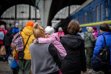 LVIV, UKRAINE - 02 Nisan 2022 Ukrayna savaşı. Annemin omzundaki küçük kız. Mariupol, Berdyansk, Kryvyi Rih 'ten gelen mülteciler Lviv Tren İstasyonu' ndaki Avrupa 'ya kaçıyorlar..