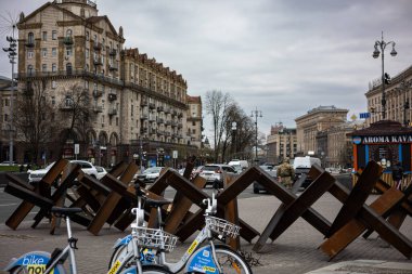 KYIV, UKRAINE - APR 20, 2022: Yol kenarındaki kirpiler veya Çek kirpileri bir saldırı durumunda Bağımsızlık Meydanı 'nı kapatmaya hazırlar. Ön planda şirket bisikletlerini paylaşmak.