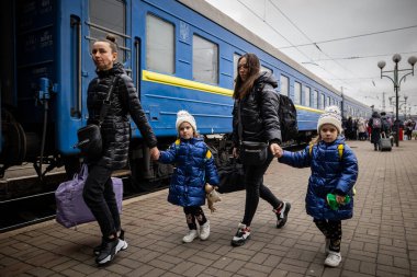 LVIV, UKRAINE - 02 Nisan 2022 Ukrayna savaşı. Mülteciler - Mariupol, Berdyansk, Kryvyi Rih 'ten gelen tahliye trenindeki ikiz kızlar, anne ve büyükanne, Lviv Tren İstasyonu' ndaki Avrupa 'ya kaçıyorlar..