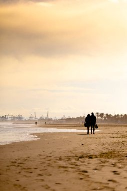 Valencia, İspanya 'da Malvarrosa' nın güneşli sonbahar plajlarında yaz titreşimleri. Deniz kıyısındaki engin, pürüzsüz kumlar tatilcileri köpüklü dalgalar boyunca yapayalnız yürüyüşlere çeker..