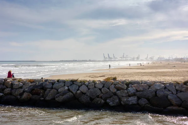 Summer vibes on the sunny autumn beach of Malvarrosa in Valencia, Spain. Vast expanses of smooth fine sand on the sea coast attract vacationers to solitary walks along the bubbling foamy waves.