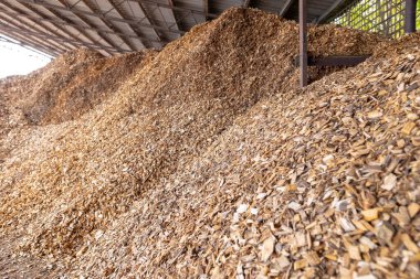 piles of hardwood wood chips are stored under the canopy as solid fuel