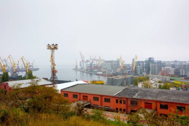 Odesa, Ukraine - OCT 22 2019: Autumn fog in the sea cargo port. Gantry cranes, level luffing cranes in the container terminal and terminal for grains of wheat, soy and other grains and oilseeds