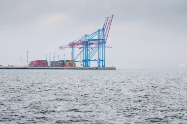 Odesa, Ukraine - OCT 21 2019: Autumn fog in the sea cargo port with side loaders. Gantry cranes and other port infrastructure in the container terminal.