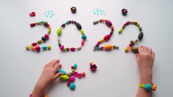 De inscriptie 2022 gemaakt van veelkleurige kralen op een witte achtergrond — Stockvideo