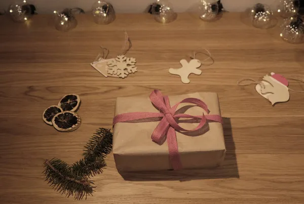 Close up of a Christmas cardboard box with red ribbon on a wooden background — Stock Photo, Image