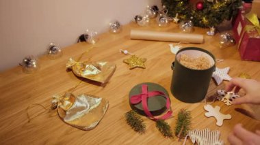 Kadınların elleri Noel hediyesini karton bir kutuya koyar.