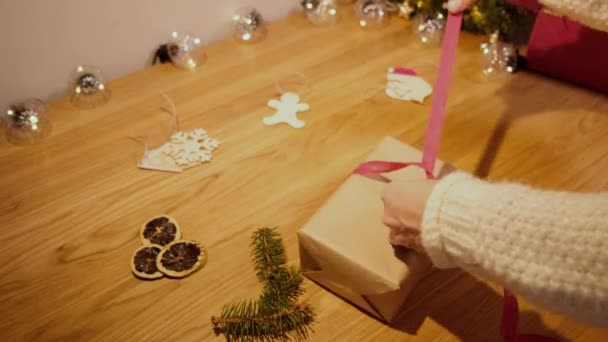 Frauenhände wickeln ein Weihnachtsgeschenk in Bastelpapier — Stockvideo