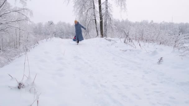 美しいですシニア女性で黄色の帽子と青のコートが下の丘を走っている. — ストック動画