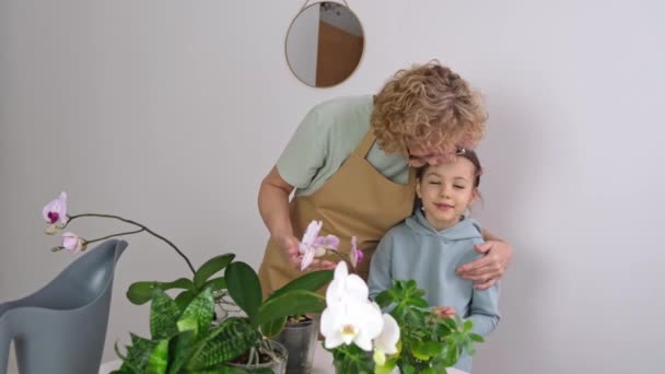 Senior Woman hugs her granddaughter and enjoy her orchids House Plants — Stock Video