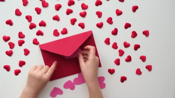 Childs manos ponen corazones de San Valentín rosa en un sobre rojo — Vídeo de stock