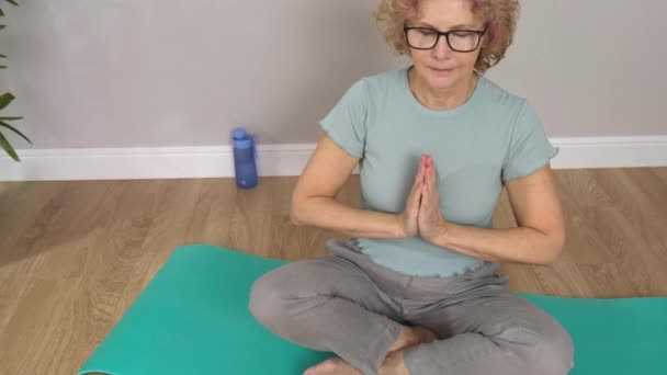 Senior hermosa mujer deportiva con gafas plegables estera para yoga — Vídeo de stock