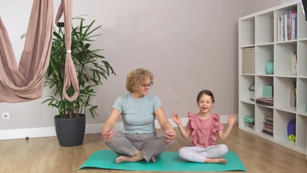 Nonna e un po 'sono seduti su un tappeto blu e meditano. — Video Stock
