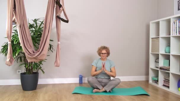 Senior bella donna sportiva che indossa gli occhiali sta meditando — Video Stock